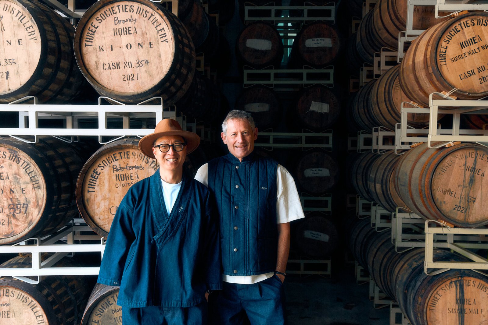 Ki One founder Bryan Do and master distiller Andrew Shand standing together among aging whisky casks at the distillery