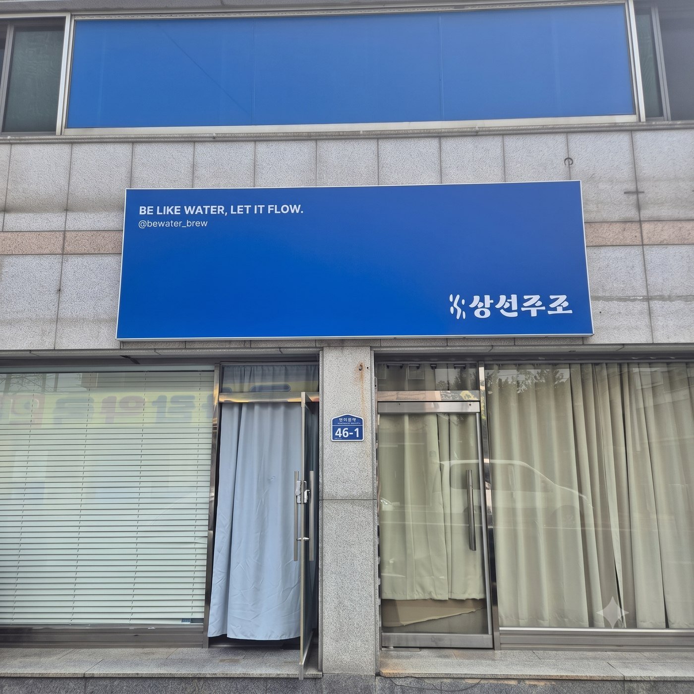 Sangsunjujo's storefront sign reading BE LIKE WATER, LET IT FLOW above the brewery entrance
